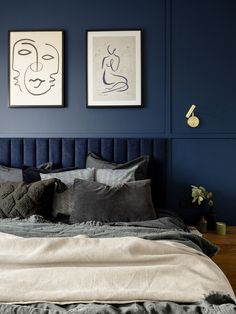 a bedroom with blue walls and artwork on the wall