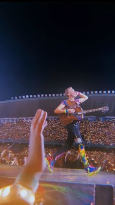 a man with a guitar on stage in front of an audience at a concert or show