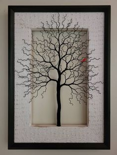 a shadow of a tree with a red bird on it's branch in a white frame