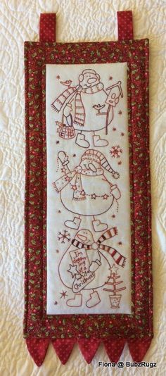 a white wall hanging with red trimmings and an image of a snowman on it