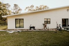 a dog is standing in front of a white brick house with tools on the lawn