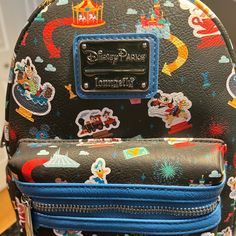 Disneyland Play At The Parks Carry Around Happy Memories Of Your Disney Trips With This Mini Backpack From Loungefly. The Simulated Leather Design Has A Colorful Allover Pattern Featuring Your Favorite Attractions, Characters, And Snacks. It Will Get You Excited About Your Next Visit To The Happiest Place On Earth! Simulated Leather Grain Mini Backpack Double Zipper Main Compartment Loungefly Logo Metal Pulls Silvertone Hardware Adjustable Padded Shoulder Straps Top Carry Handle Side Slip Pocket Black Backpack For Theme Park, Black Disney Bag For Theme Park, Black Disney Backpack For Travel, Black Disney-style Bag For Theme Park, Black Disney Style Bag For Theme Park, Themed Black Backpack For Everyday Use, Black Backpack For Theme Parks, Themed Black Backpack For Theme Parks, Fun Black Standard Backpack