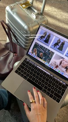 a woman sitting on the ground with her laptop in front of her and luggage behind her