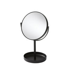 a round mirror sitting on top of a metal stand