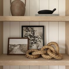 two wicker baskets sit on top of a shelf in front of a vase and other items