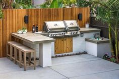 an outdoor kitchen with two grills and stools