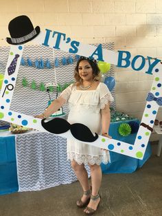 a pregnant woman standing in front of a sign that says it's a boy