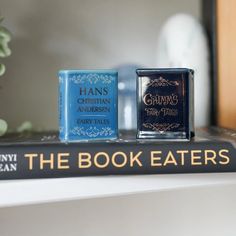 two books sitting on top of each other next to a vase with flowers in it