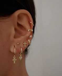 a close up of a person wearing ear piercings with cross and star designs on them