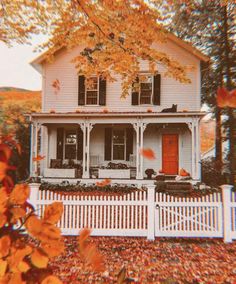 a white house with autumn leaves on the ground