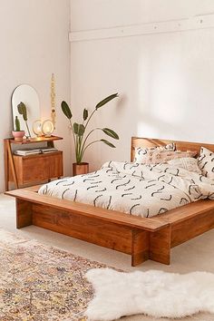 a bed sitting on top of a wooden platform next to a white rug and potted plant