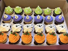 a box filled with lots of cupcakes covered in frosting and decorated to look like monsters