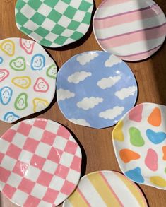 six plates with different designs on them sitting on a wooden table next to each other