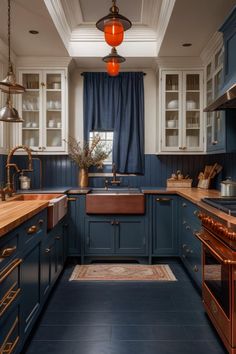 a kitchen with blue cabinets and wooden counter tops, an orange light hanging from the ceiling