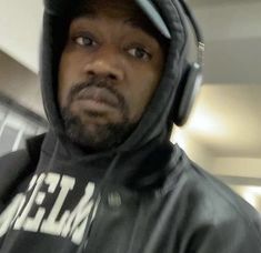 a man in a hoodie is wearing headphones and looking at the camera with an intense look on his face