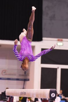 a person doing a handstand on the balance beam