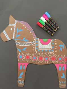 a wooden horse with crayons next to it