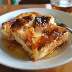 two pieces of french toast on a plate with honey syrup and a fork next to it