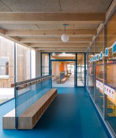 a long bench sitting in the middle of a room next to a glass wall and blue floor