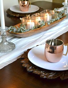 a table with candles, plates and cups on it