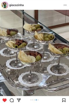 several glasses filled with olives and chips on top of a glass serving platter