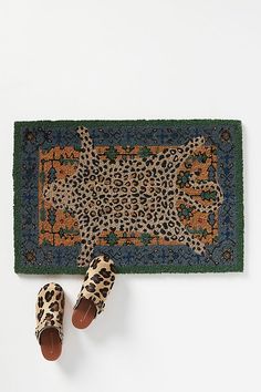 a pair of leopard print slippers sitting on top of a rug next to shoes