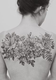 the back of a woman's shoulder with flowers and leaves tattooed on her upper