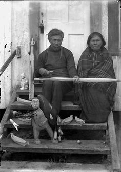 an old black and white photo of two people sitting on steps