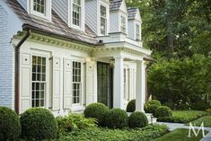 a white house with lots of windows and bushes