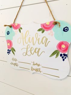 a wooden sign with flowers on it hanging from a wall