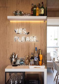 there is a bar with bottles and glasses on the shelf next to it that says yes please