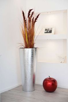 an apple sitting next to a metal planter with grass in it on the floor