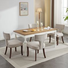 a dining room table with four chairs and a white rug on the floor in front of it