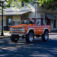 an orange pick up truck driving down the street