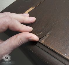 a person's hand is holding the edge of a piece of wood that has been stained brown