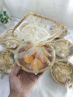 a hand holding a mesh bag filled with oranges on top of a white table