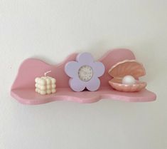 a pink shelf with shells and a clock on it