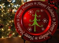 a red christmas plate sitting in front of a tree with snowflakes on it