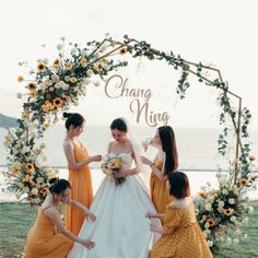 four women in yellow dresses are standing under an arch with sunflowers on it