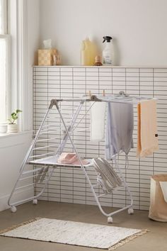 an ironing board with clothes hanging on it in front of a white tiled wall