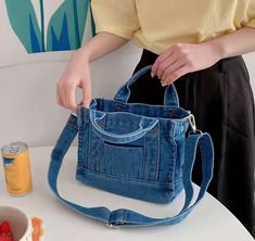 a woman is holding a denim bag with strawberries on the table next to it