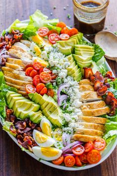 a salad on a plate with dressing next to it