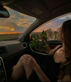 a woman sitting in the driver's seat of a car with flowers on the dashboard