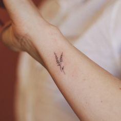 a woman's arm with a small flower tattoo on the left side of her arm