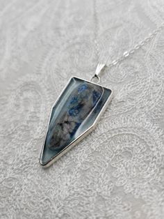 This beautiful handmade, one-of-a-kind silver pendant with a real Blue Apatite Stone accent is perfect for dressing up or down. This pendant has approximately a height of 2 in. x 1 in. in length and is made from a durable silver metal alloy, and stone set in blue mica tinted resin. Unique Sterling Silver Necklace For Memorial, Silver Gemstone Necklaces For Keepsake, Unique Blue Rectangular Pendant Jewelry, Silver Gemstone Jewelry For Memorial, Unique Blue Keepsake Necklace, Blue Sterling Silver Amulet Jewelry, Sterling Silver Rectangular Pendant For Memorial, Sterling Silver Rectangular Pendant Keepsake Jewelry, Silver Jewelry With Large Pendant For Keepsake