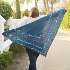 a woman is walking down the street with a blue shawl