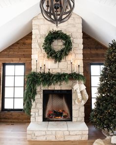 a fireplace decorated for christmas with wreaths and candles