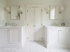 a white bathroom with double sinks and mirrors