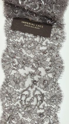 an item is displayed on a white surface with black and silver lace, which has been sequinized onto it