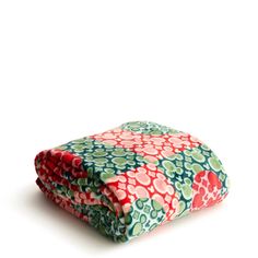 a red, green and blue flowered blanket folded on top of each other in front of a white background